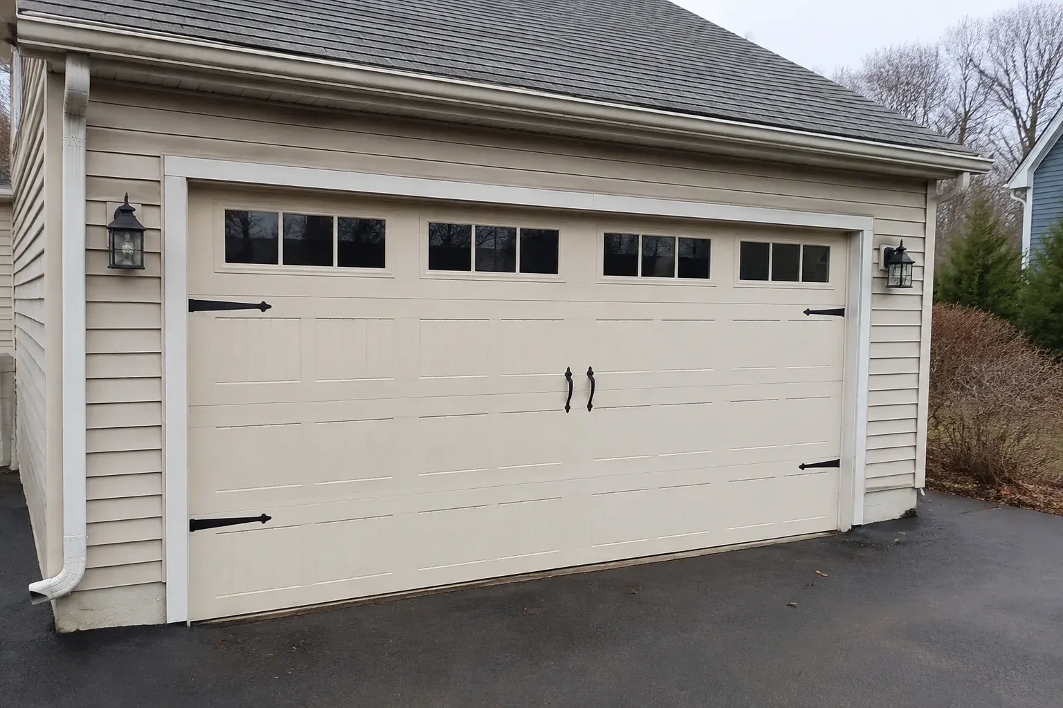 Cream carriage-house-style garage door with dark decorative hardware. — Carriage-House Garage Door Installation, Waterloo