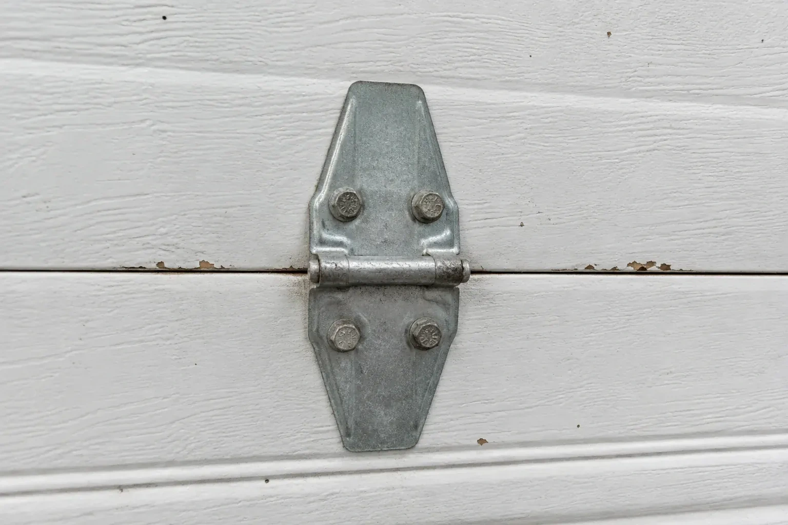 Metal center hinge across a seam in a white sectional garage door. — Garage Door Hinge Replacement, Waterloo